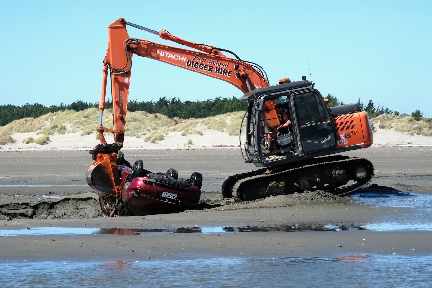 Digger removes abandoned car stuck in the sand, December 2020. 