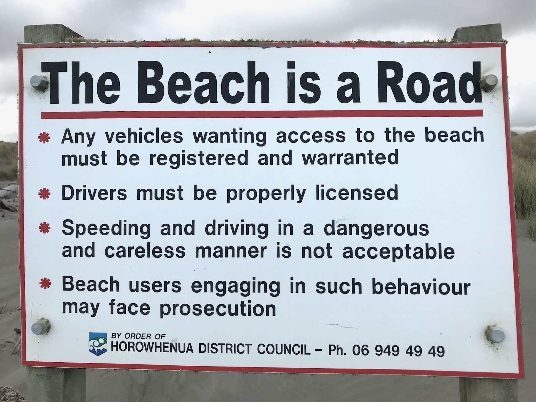 The beach is a road, sign on beach. 