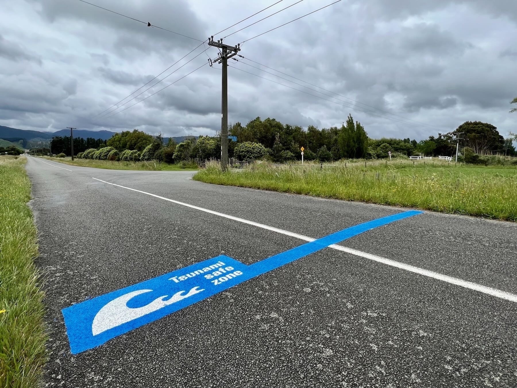 New Tsunami Safe Zone road marking — blue line near the intersection with Takapu Road. 